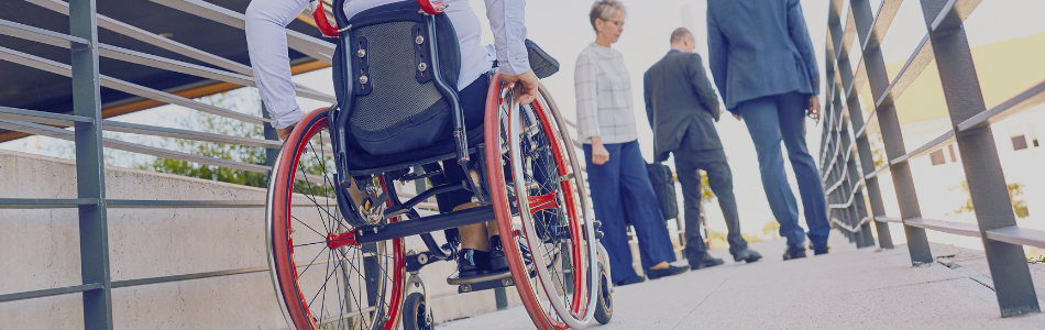 person on a wheelchair alongside other people on a ramp