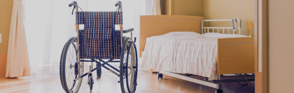 empty bed and wheelchair in a nursing home room